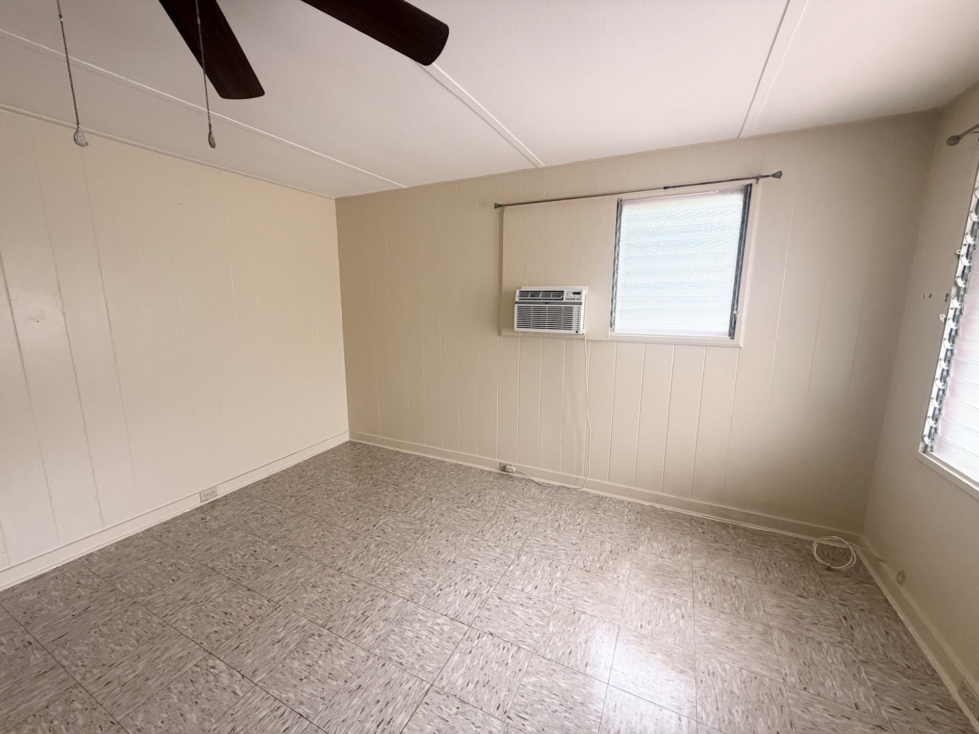 A room with a ceiling fan and a window with blinds.